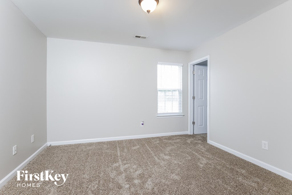 a spacious living room with carpet and a door to a bedroom