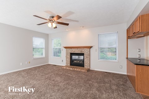 A living room with a fireplace and a ceiling fan.