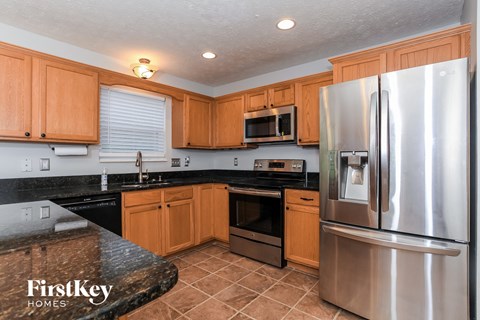 A kitchen with wooden cabinets and a stainless steel refrigerator.