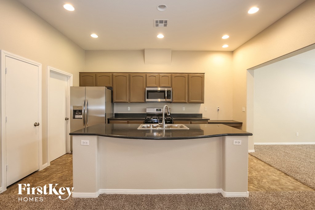 A kitchen with a black countertop and brown cabinets.
