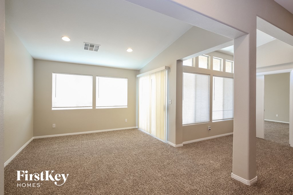 A spacious room with a carpeted floor and a large window.