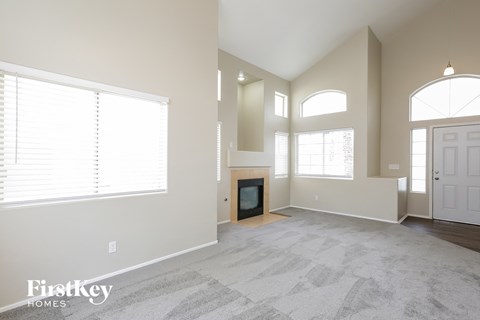 an empty living room with a fireplace and large windows