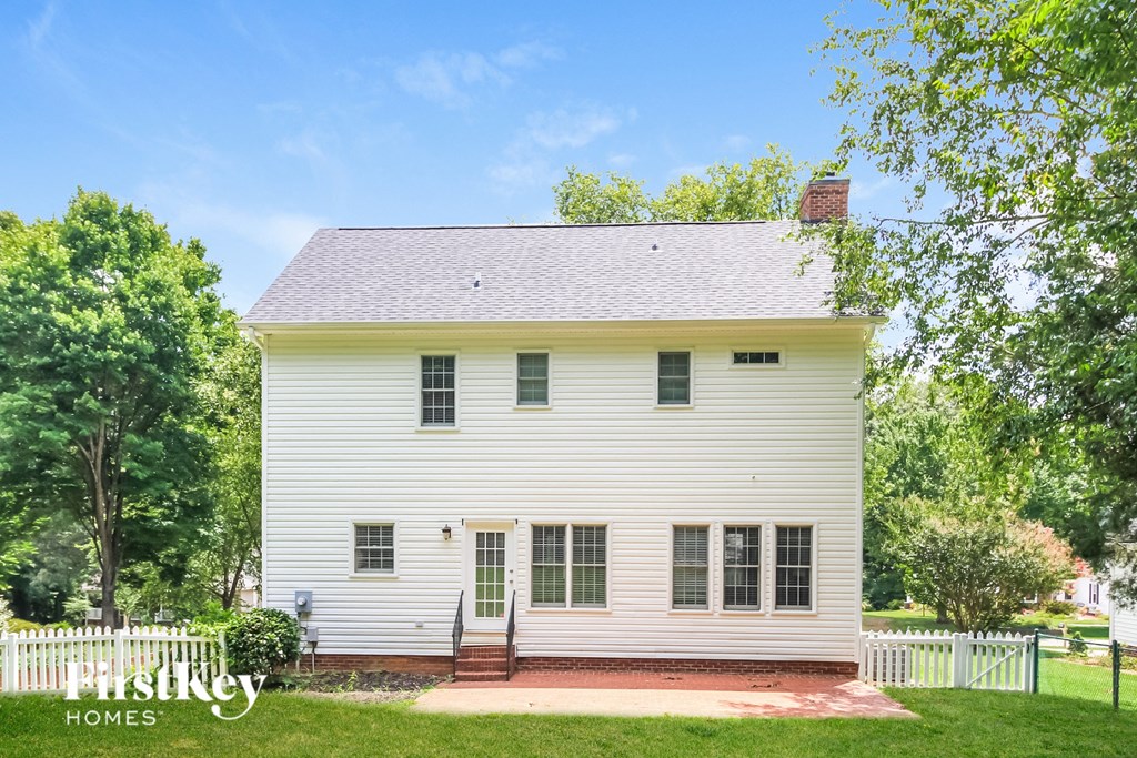 a white house with a white picket fence and trees