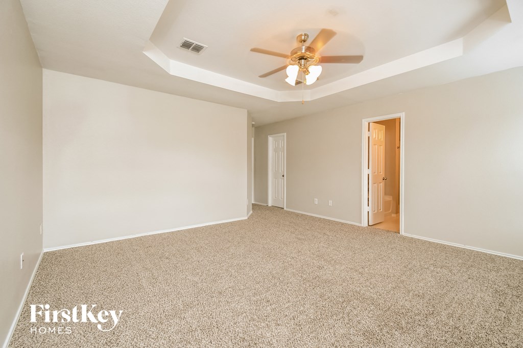 a empty living room with a ceiling fan and a white wall