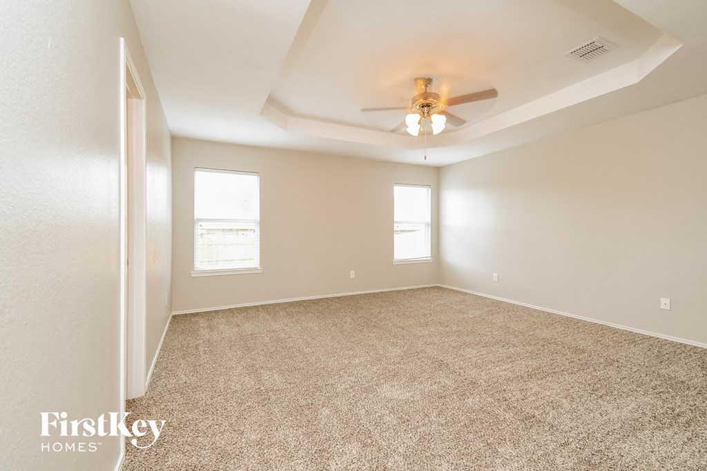 the spacious living room with ceiling fan and carpeting