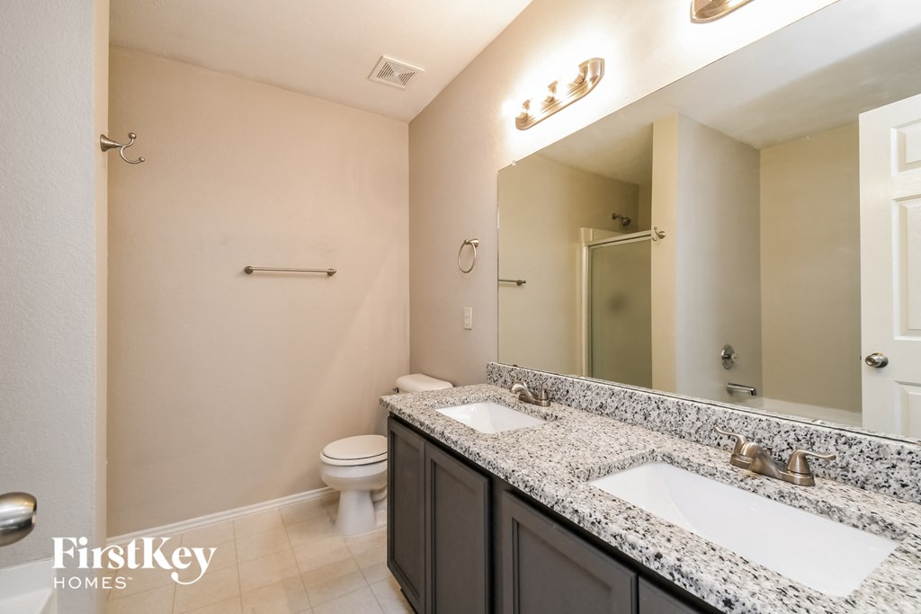 a bathroom with two sinks and a toilet and a mirror