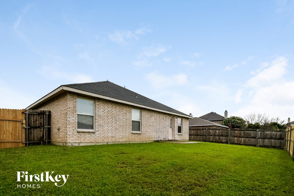 a backyard with a brick house and a wooden fence