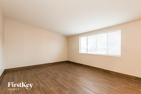 A room with wooden flooring and a window with blinds.