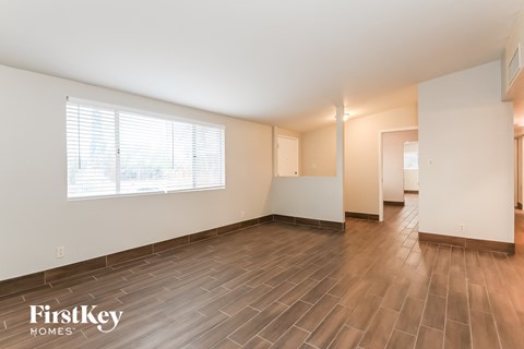 A spacious room with wooden flooring and a large window.