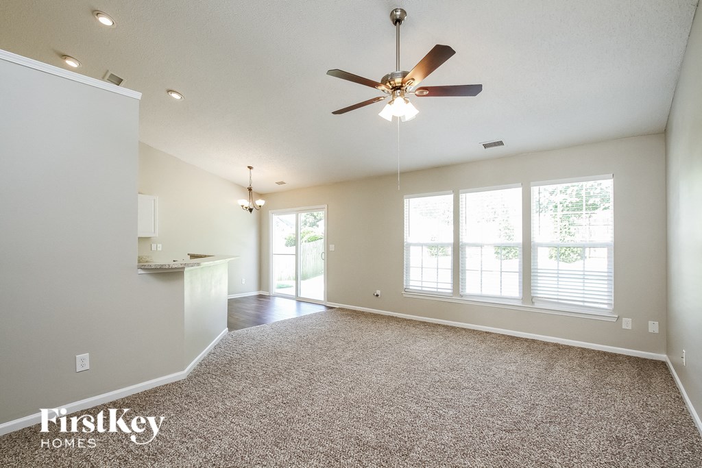 A spacious room with a ceiling fan and carpeted floor.