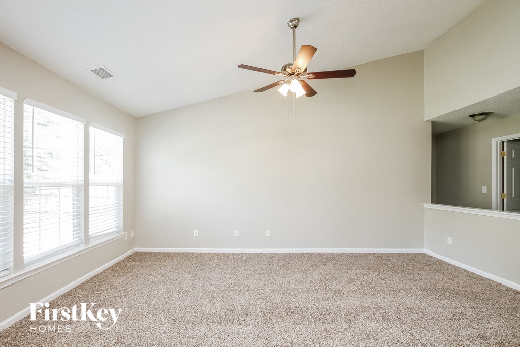 A room with a ceiling fan and a carpeted floor.