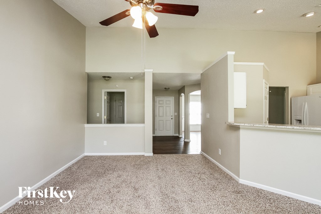 A spacious room with a carpeted floor and a ceiling fan.