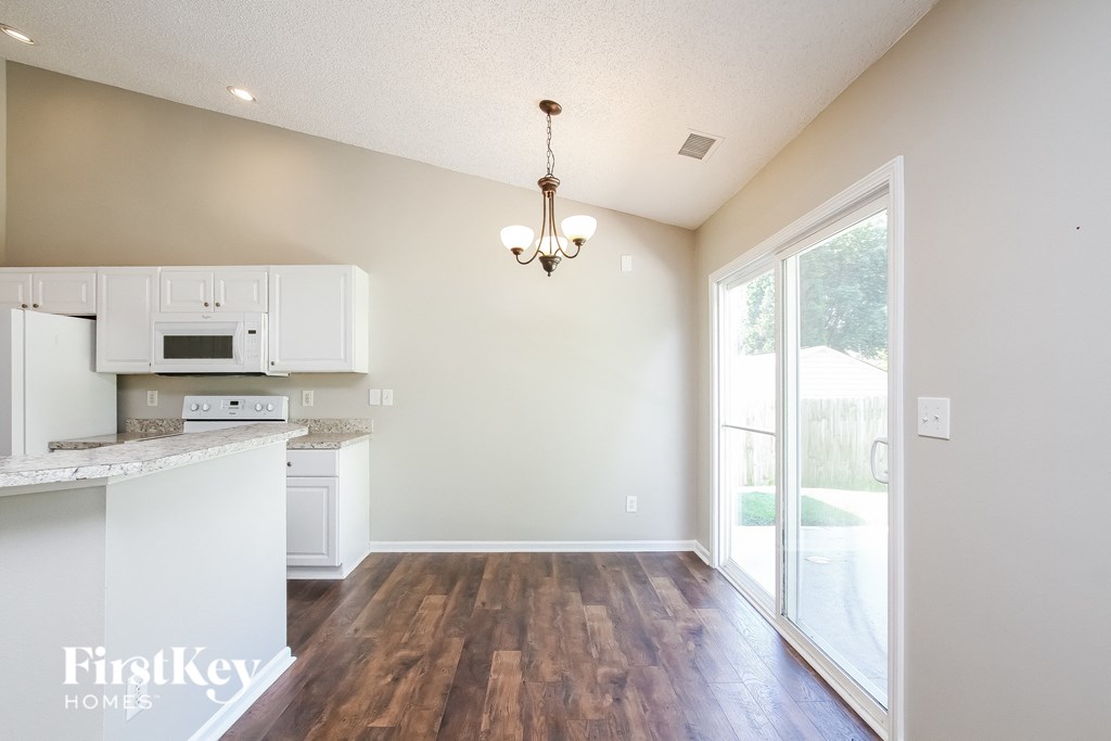 A kitchen with white appliances and wooden floors.