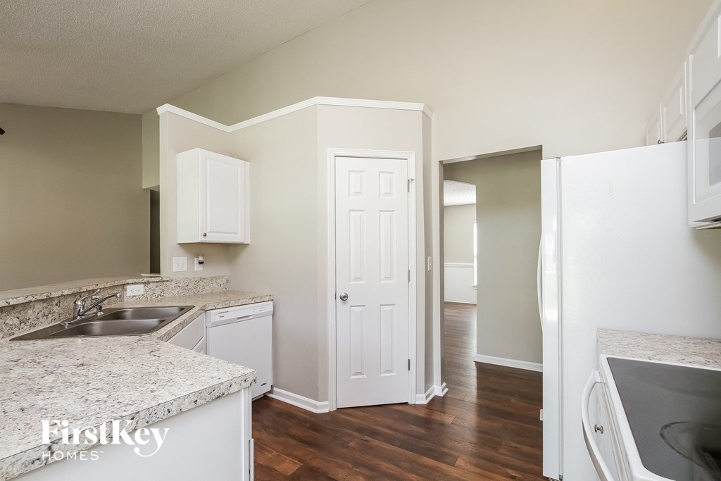 A kitchen with a sink, cabinets, and a refrigerator.
