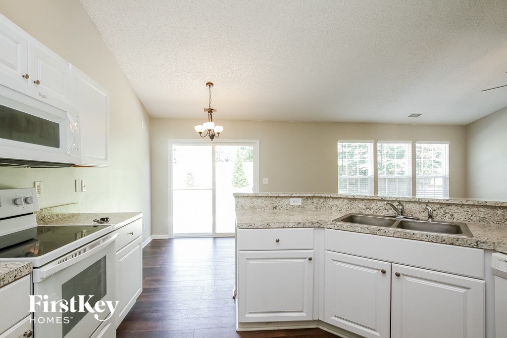 A kitchen with white cabinets and a stove top oven.