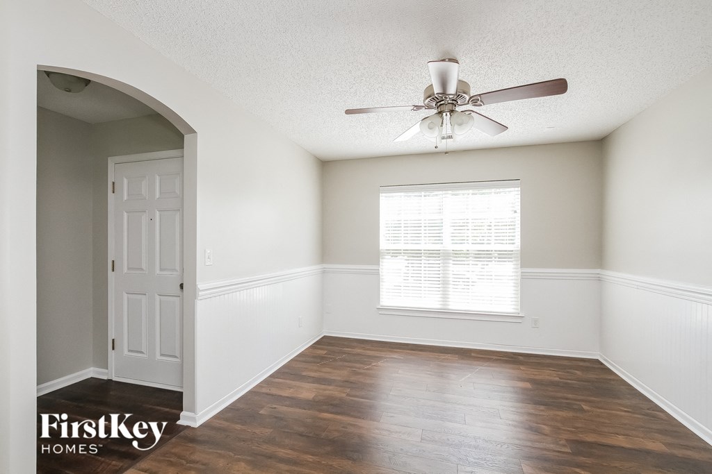A room with a ceiling fan and wooden floors.