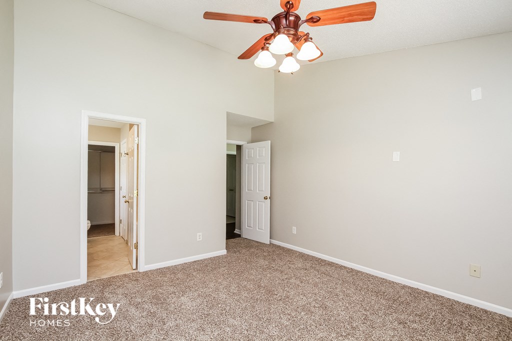 A room with a ceiling fan and carpeted floor.