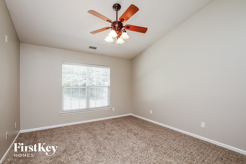 A room with a ceiling fan and a window with blinds.