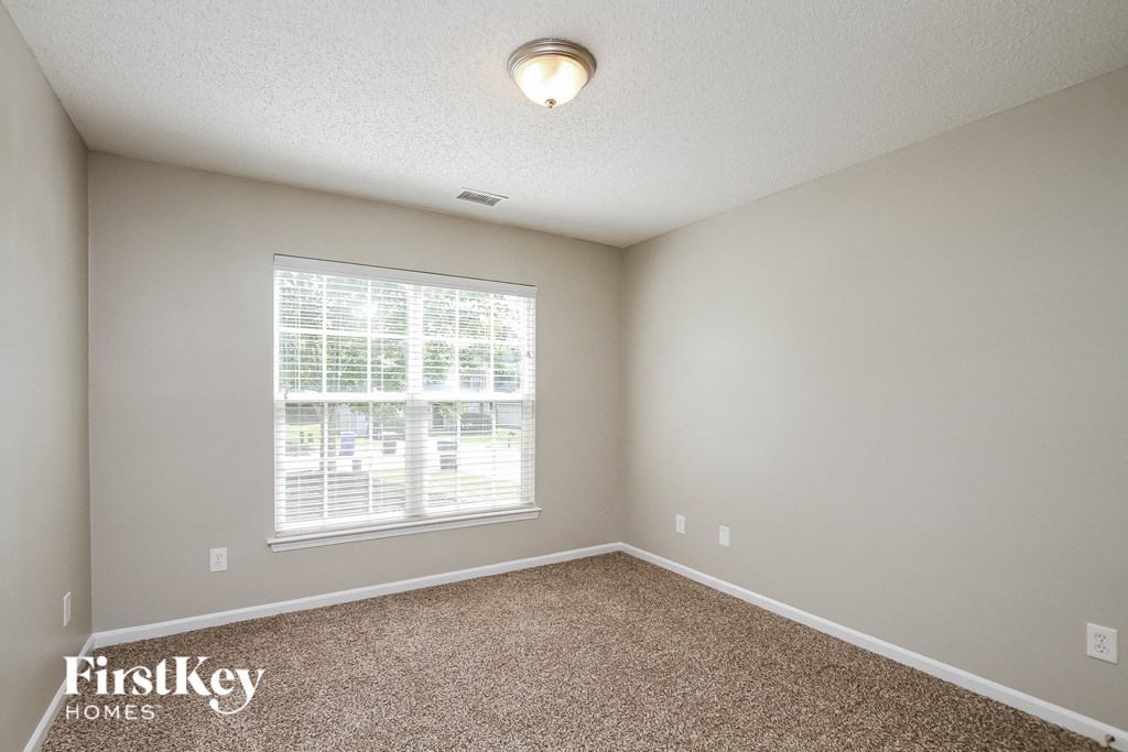 A room with a carpeted floor and a window with blinds.