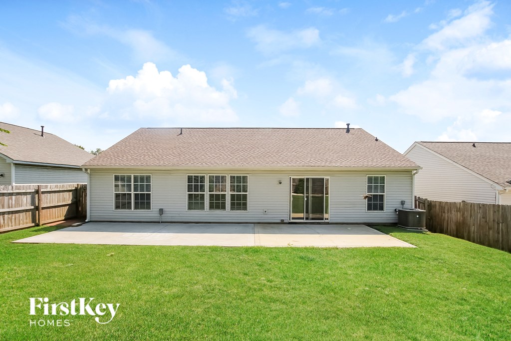 A white house with a brown roof and a green lawn in front.