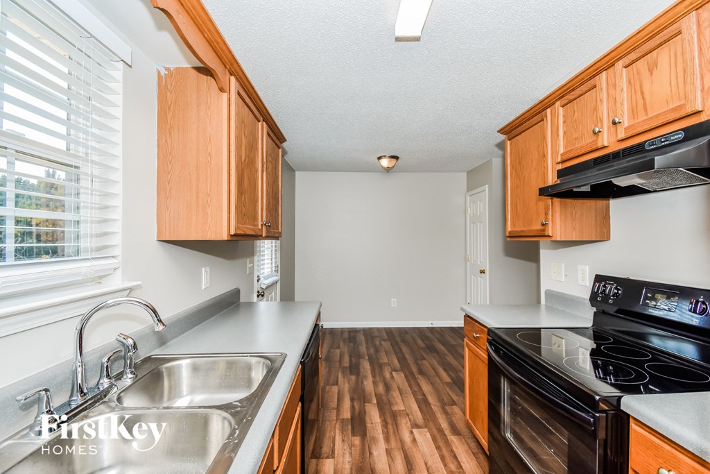 a kitchen with wooden cabinets and a stove top oven and a sink