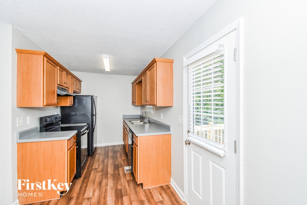 a kitchen with wooden cabinets and black appliances and a window