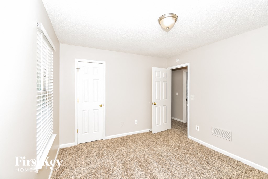 a spacious living room with two doors and a door to a closet