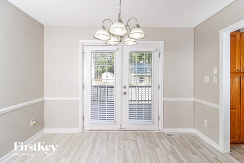 a dining room with white doors and a chandelier
