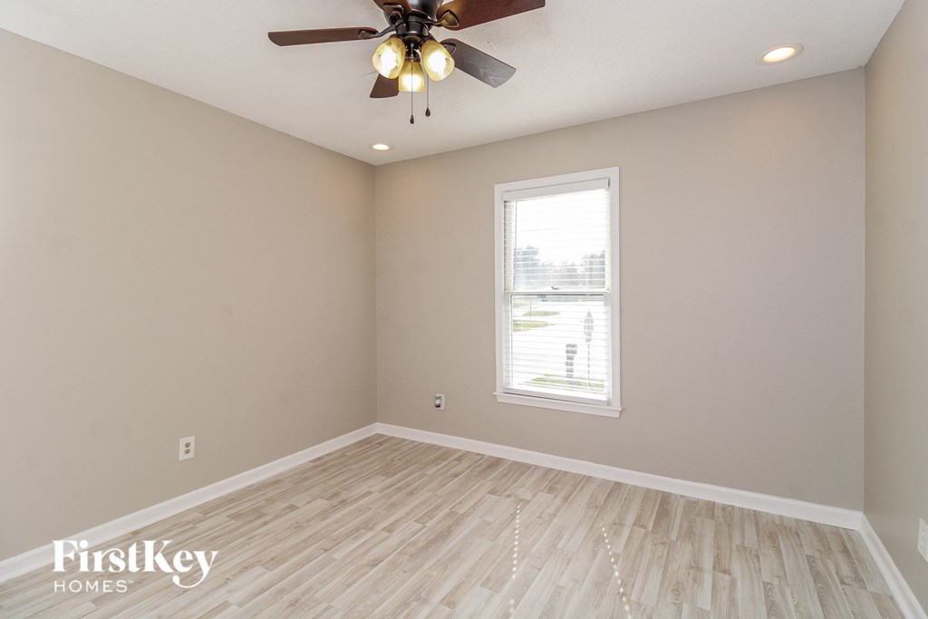 the spacious living room with hardwood floors and a ceiling fan
