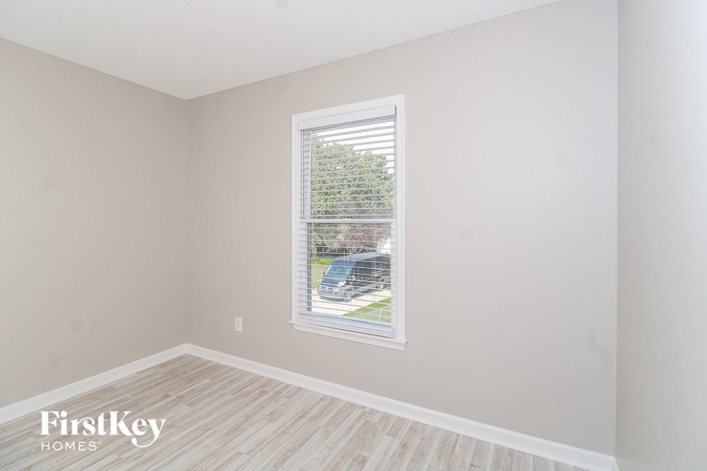 a bedroom with a large window and wooden floors