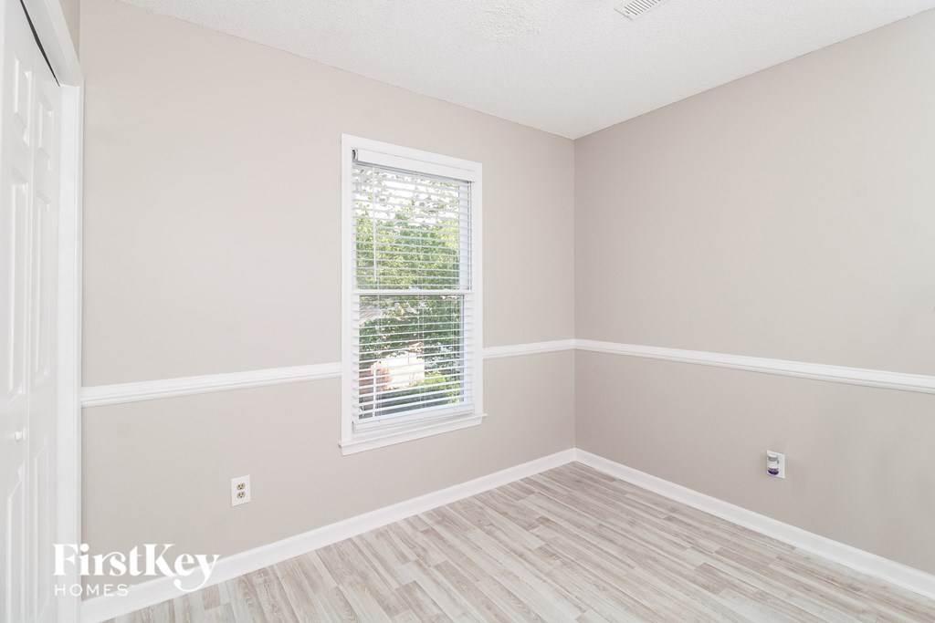 a bedroom with a window and a hardwood floor