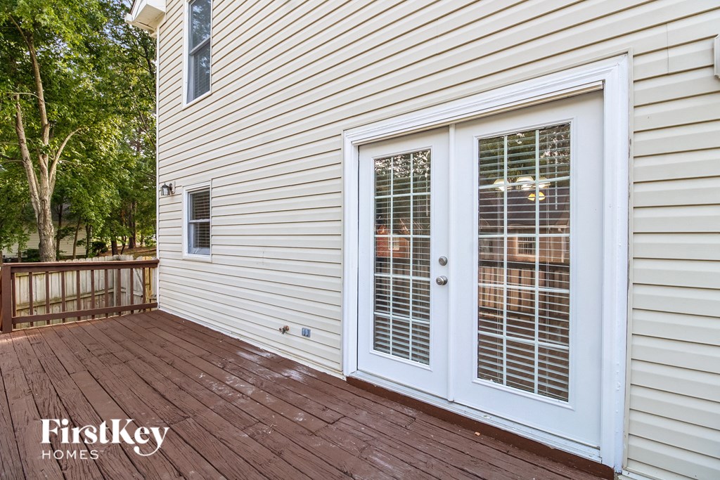 a deck with white vinyl siding and a white door