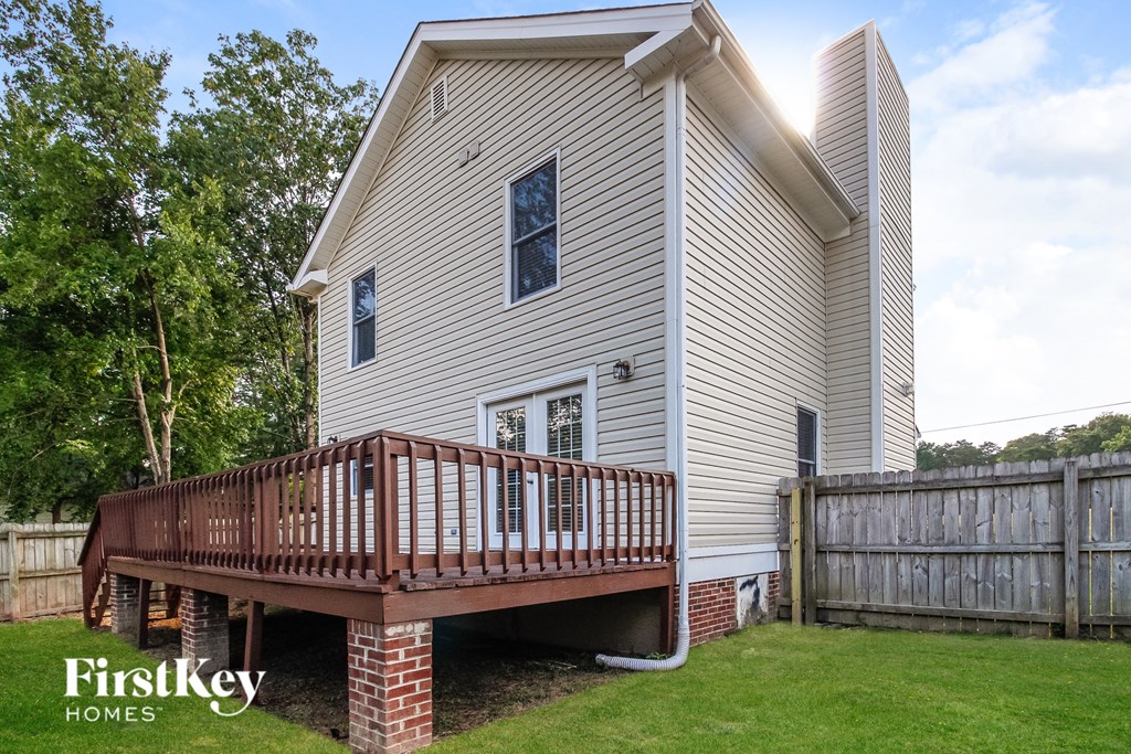 the back of a house with a deck and a wooden fence