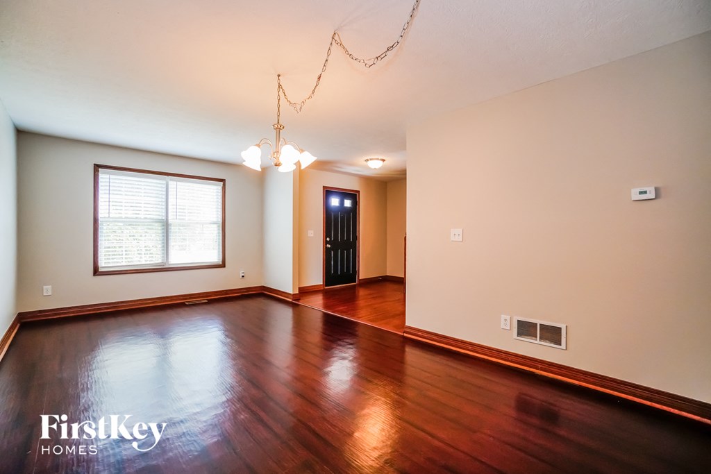 A room with wooden floors and a chandelier hanging from the ceiling.