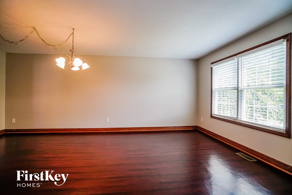 A room with wooden floors and a window showing trees outside.