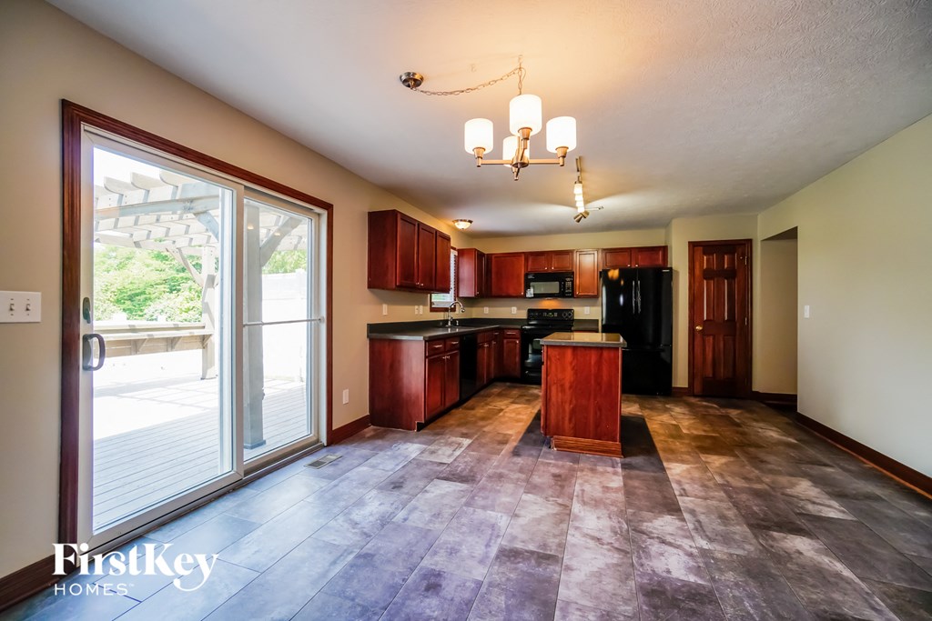 A kitchen with wooden cabinets and a black refrigerator.