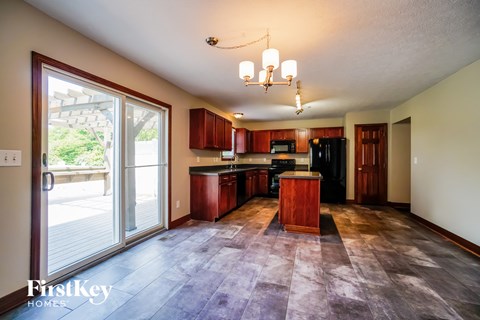A kitchen with wooden cabinets and a black refrigerator.