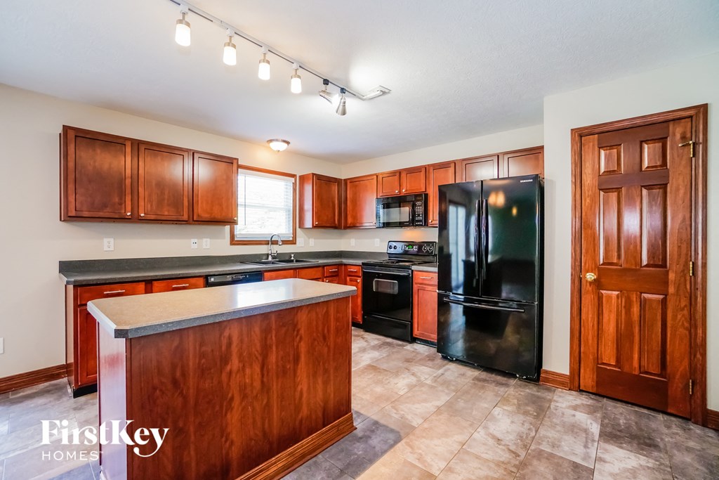 A kitchen with wooden cabinets and a black fridge.