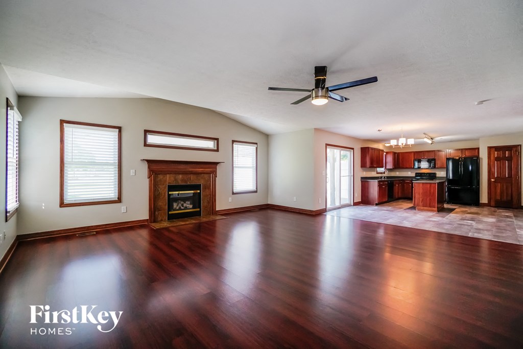 A spacious living room with wood flooring and a fireplace.
