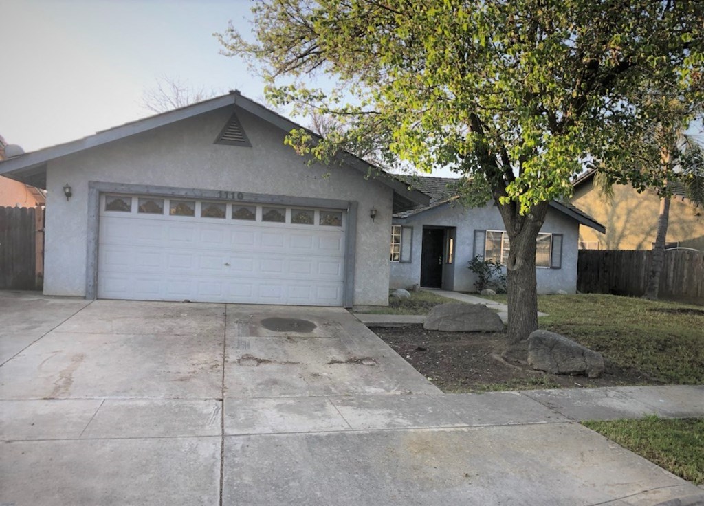 a house with a white garage door and a tree