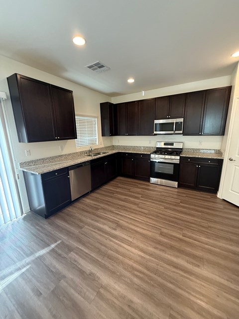 A kitchen with dark brown cabinets and a wooden floor.