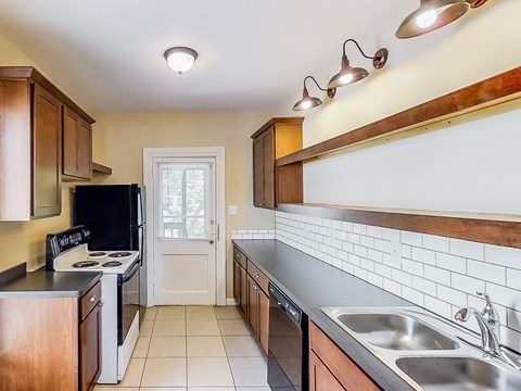 A kitchen with a black refrigerator and wooden cabinets.