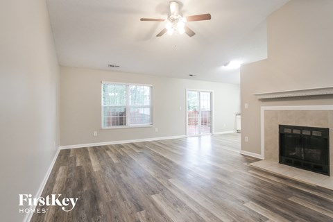 A spacious living room with a fireplace and a ceiling fan.