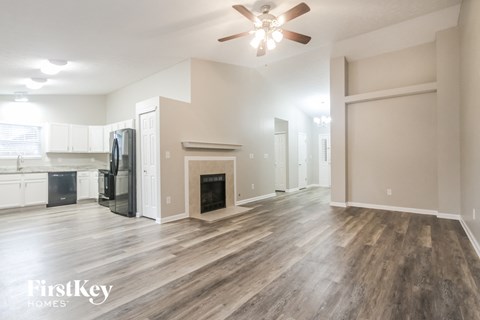 A spacious living room with wood flooring and a fireplace.
