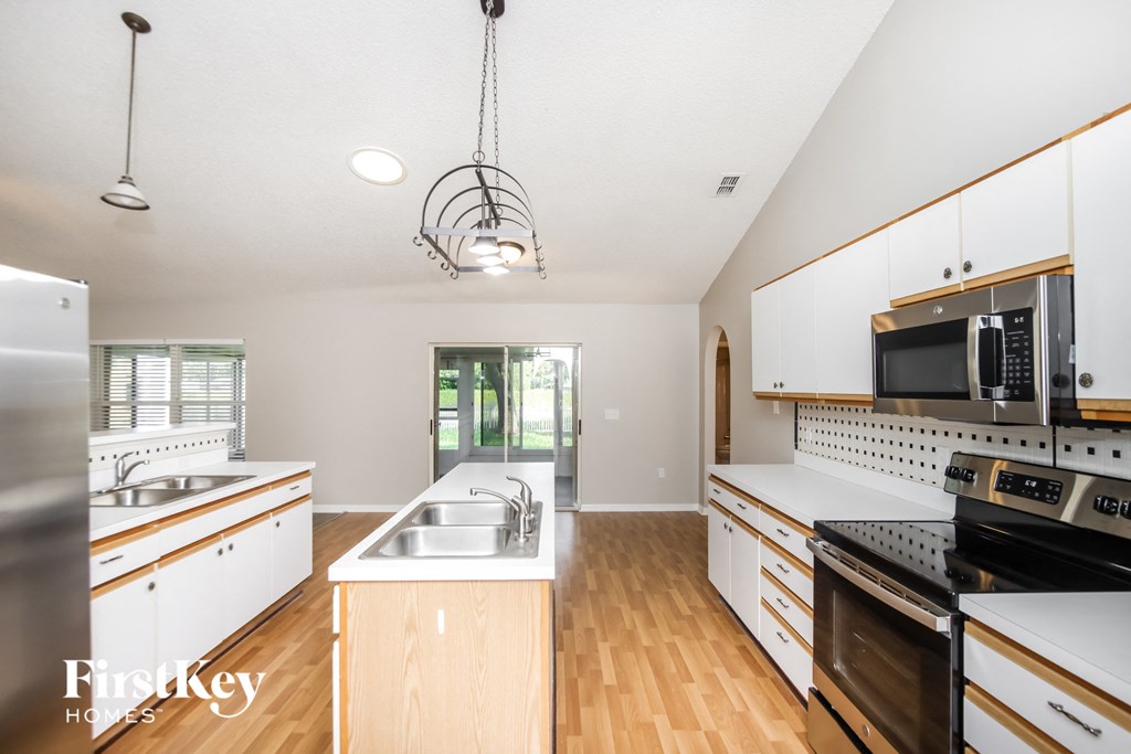 a kitchen with white cabinets and stainless steel appliances and wood floors