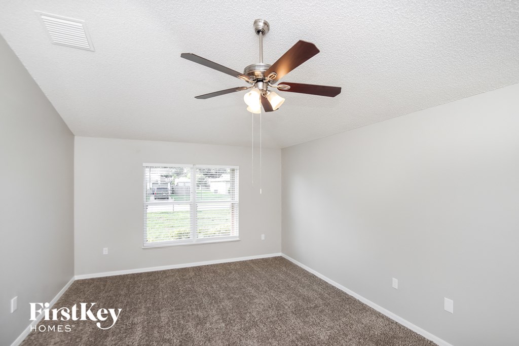 the spacious living room with ceiling fan and carpet