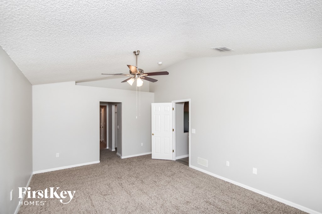 a spacious living room with white walls and a ceiling fan