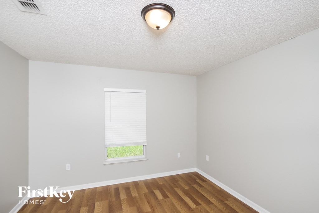 a bedroom with a window and a wooden floor