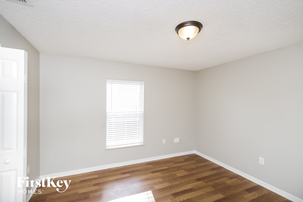 the spacious living room with hardwood flooring and a window