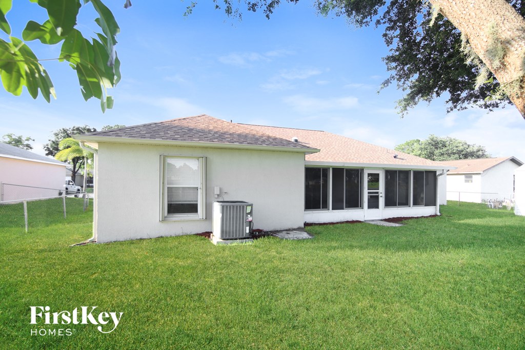a small white house with a grass yard and a tree